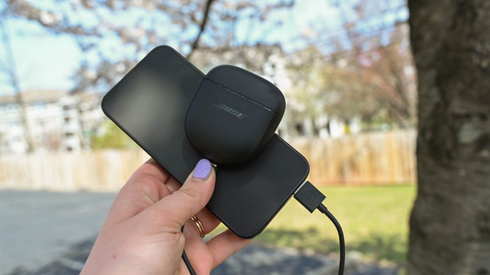 Person holding a Bose earbuds case being charged by the Mophie Powerstation